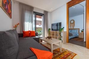 ein Wohnzimmer mit einem grauen Sofa und orangefarbenen Kissen in der Unterkunft Welcome Home Palmiers in Casablanca