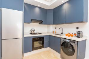 eine Küche mit blauen Schränken und einer Waschmaschine und einem Trockner in der Unterkunft Welcome Home Palmiers in Casablanca