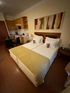 une chambre d'hôtel avec un grand lit et une cuisine dans l'établissement Semanas 30 e 24 Vila Galé Cerro Alagoa, à Albufeira