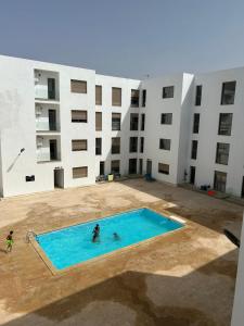 2 personnes dans une piscine en face d'un bâtiment dans l'établissement APPART AGADIR BAY CENTRE PISCINE PLAGE À 5mnts À PIEDS, à Agadir