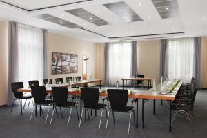 una sala de conferencias con una mesa larga y sillas en IntercityHotel Magdeburg, en Magdeburgo