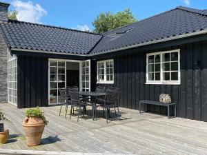 a black shed with a table and chairs on a deck at Modern Retreat in Marielyst - By Traum Ferienwohnungen in Marielyst