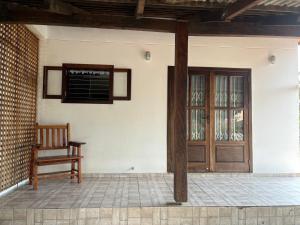a porch with a wooden door and a chair at Casa agradável in Indaial