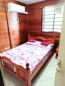 a bed in a room with a wooden wall at Kreyolita in Saint-Laurent du Maroni