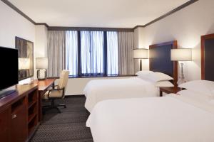 a hotel room with two beds and a desk and a television at Sheraton Anchorage Hotel in Anchorage