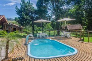 a swimming pool on a wooden deck with umbrellas at Casa de Barro - Chalés in Santo Antônio do Pinhal