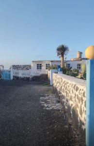 a stone wall with a palm tree and buildings at Cabaña Amida in Lajares