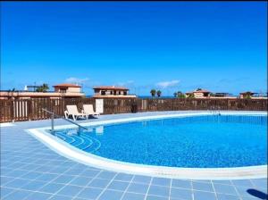 a large swimming pool with two chairs next to a fence at Cabaña Amida in Lajares