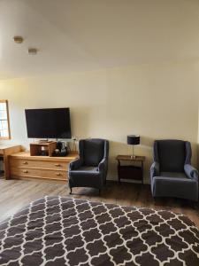 a living room with two chairs and a flat screen tv at Covered Bridge Inn in Sussex