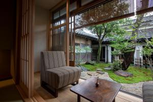 un soggiorno con una sedia e un tavolo di 越中井波町屋旅館古香里庵 a Nanto
