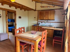a kitchen with a wooden table and some chairs at Cabañas Rustikas in Pichidangui