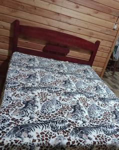 a bed with a black and white quilt on it at Sítio lampião do norte in Blinha