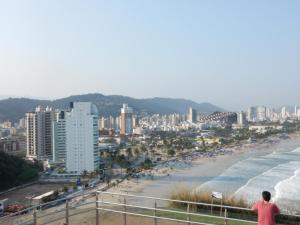 Ein Mann steht auf einem Balkon mit Blick auf den Strand in der Unterkunft CASA SETE ENSEADA AR COND Suíte E ESTACIONAMENTO GRÁTIS e uma ótima localização na enseada in Guarujá + 12 Fotos