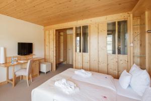 a bedroom with a bed and a desk and a television at Natur & Wellnesshotel Breggers Schwanen - Bernau im Schwarzwald in Bernau im Schwarzwald