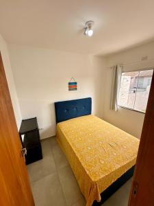 a bedroom with a bed with a yellow bedspread at Balneário Céu Azul, com piscina a 350m da praia in Matinhos