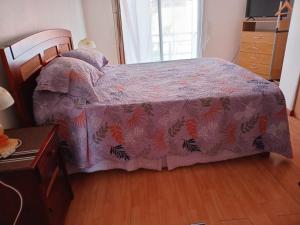 a bedroom with a bed with a purple comforter at Bienvenidos a mí casa in Quilpué