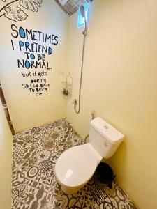 a bathroom with a toilet and a sign on the wall at katana siargao in Catagnan