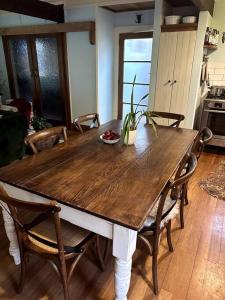 einen Holztisch in einer Küche mit Stühlen in der Unterkunft Oakura Pond Cottage - A unique kiwi holiday Bach in Oakura