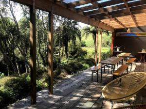 eine Terrasse mit einem Tisch, Stühlen und Bäumen in der Unterkunft Oakura Pond Cottage - A unique kiwi holiday Bach in Oakura