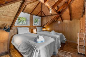 two beds in a room with wooden walls at Pinehurst Sunset Beach Cottage in Wareham