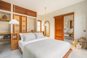a bedroom with a large white bed and a mirror at Alma Bingin Boutique Hotel in Uluwatu +60 photos