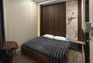 a small room with a bed with a checkered blanket at Mộc Trà Hotel in Ho Chi Minh City
