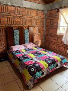 a bed in a room with a quilt on it at Hermosa Cabaña en bosque muy cerca Patzcuaro in Tupátaro