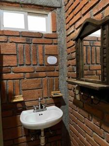 a bathroom with a sink and a brick wall at Hermosa Cabaña en bosque muy cerca Patzcuaro in Tupátaro