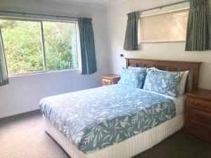 a bedroom with a bed with blue sheets and a window at The Bach Wai Rua A Waterfront Home in Opononi