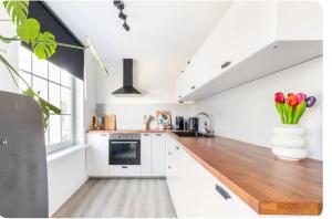 a kitchen with white cabinets and a wooden counter top at Studio Romantic in Zandvoort