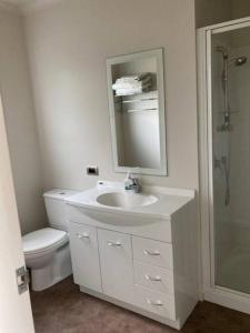 a bathroom with a sink and a toilet and a mirror at The Bach Wai Rua A Waterfront Home in Opononi