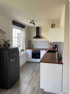 a kitchen with a black refrigerator and white cabinets at Studio Romantic in Zandvoort +4 photos
