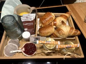 a wooden tray with a box of bread and croissants at Chambre Parenthèse Cosy et institut in Neufmarché +10 photos