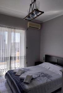 a bedroom with a bed and a large window at SWEET APPARTMENT in Patra