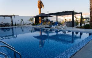 una piscina con sillas y una palmera en Venue Luxury Chalet, en Al Rama