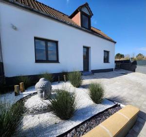 a white house with a statue in front of it at Maison jacuzzi privé - séjour détente 7personnes in Étaples