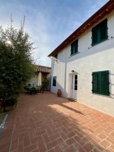 a white house with a brick patio in front of it at Casa vacanze Eny in Capannori