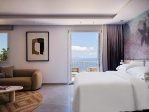 Deos Mykonos - A Myconian Collection Hotel في مدينة ميكونوس: غرفة نوم بسريرين وإطلالة على المحيط