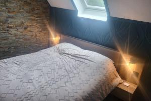 a bedroom with a bed with a brick wall at Logement Cosy type Loft près de Saint Quentin in Marcy