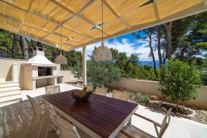 an outdoor dining area with a wooden table and chairs at Villa Bruna in Sumartin
