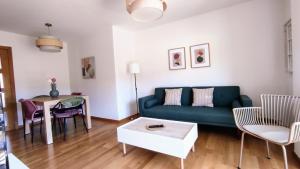 a living room with a green couch and a table at Un rincón con vistas a la Ría, playa y parking. in Ribeira +25 photos