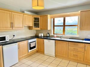 a kitchen with wooden cabinets and white appliances at No's 6, 8 & 9 Dingle Lispole Holiday Homes in Lispole