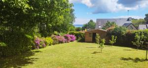a garden with a house and trees and flowers at Nid douillet Les Mouettes in Fouesnant
