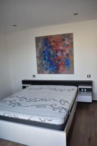 1 cama en una habitación con un cuadro en la pared en superbe villa neuve, en Aytré