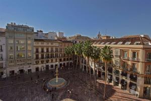 una calle de la ciudad con edificios y una fuente y palmeras en Apartamentos Plaza Constitución - Larios, en Málaga