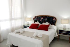 a bedroom with a large white bed with red pillows at Apartamento Infantas 26 in Sanlúcar de Barrameda