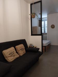 a black couch in a living room with a mirror at Le Coeur de Sel in Salins-les-Bains
