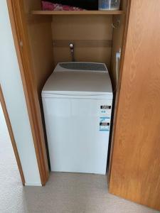 a small white refrigerator in a small closet at Spectacular Ocean View at Ruby Bay in Mapua