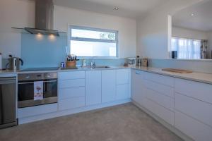 a large white kitchen with white cabinets and a window at Spectacular Ocean View at Ruby Bay in Mapua