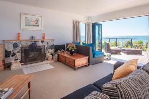 a living room with a couch and a fireplace at Spectacular Ocean View at Ruby Bay in Mapua